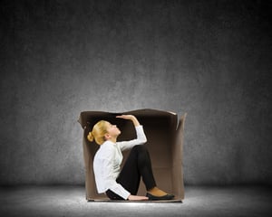 Young businesswoman sitting in carton box and feeling uncomfortable